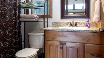 A bathroom with a toilet, a sink with a mirror above, and a shower curtain.