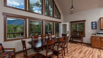 A spacious kitchen with large windows, wooden flooring, and a dining area with a table and chairs.