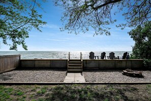 A beachside deck with a concrete staircase leading to a seating area with Adirondack chairs. - Cozy Rustic-Modern Cabin Escape with Lake Views & Fire Pit Nights in Ontario, Canada (Leamington)