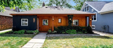 Une maison à deux étages avec un porche à l’avant, un garage en briques et une pelouse bien entretenue.