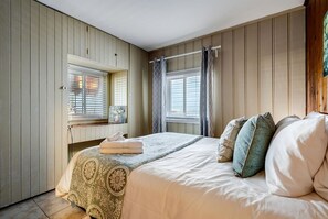 A bedroom with a bed, a window with blinds, a radiator, and a wall-mounted shelf. - Cozy Rustic-Modern Cabin Escape with Lake Views & Fire Pit Nights in Ontario, Canada (Leamington)