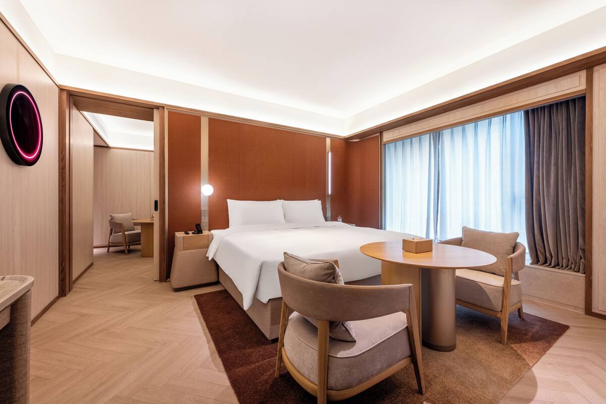 Una habitación de hotel con cama, mesita de noche, silla y escritorio con otra silla.