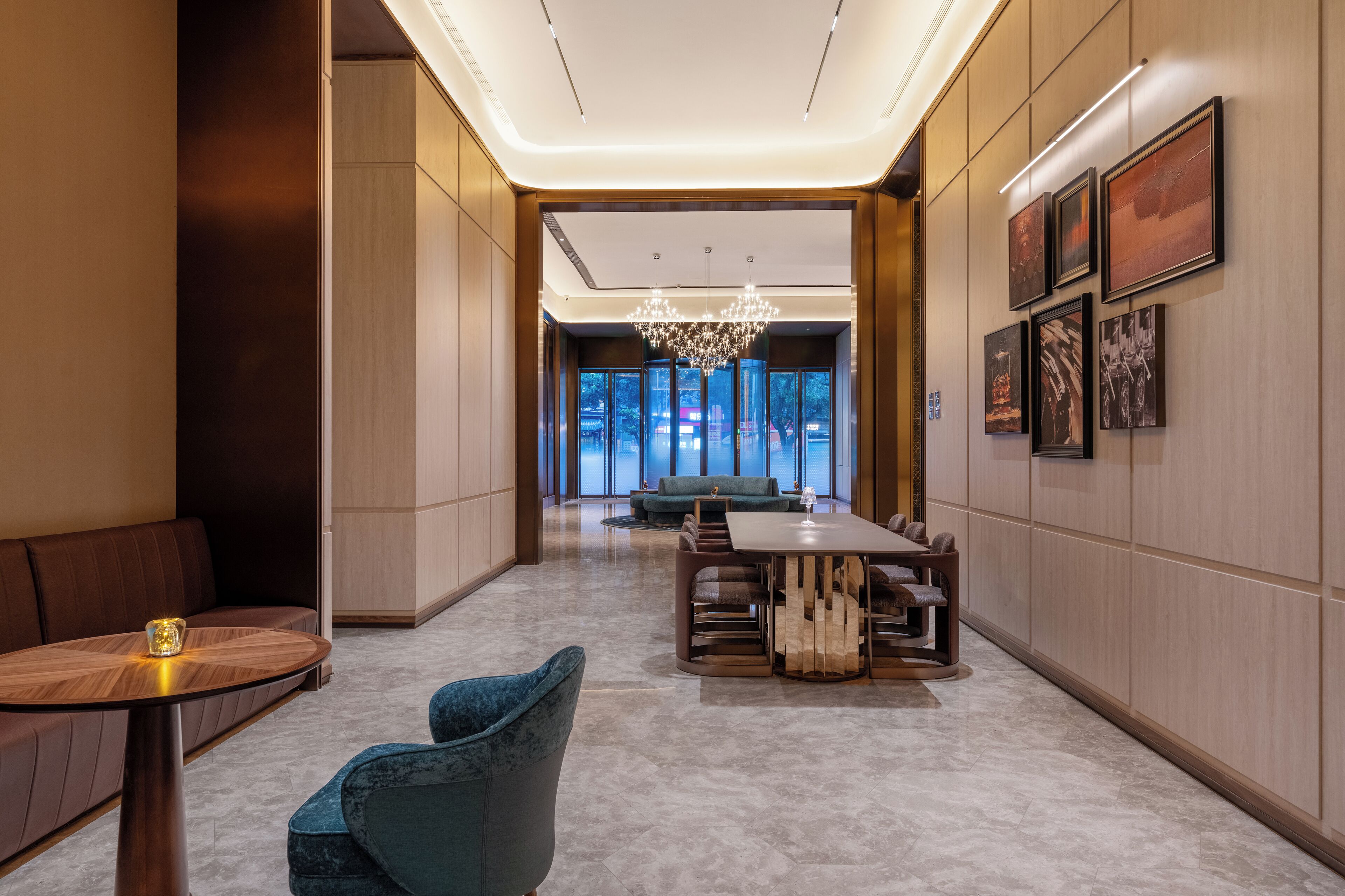 Un hall d’hôtel moderne, doté d’un espace salon, d’un lustre et d’œuvres d’art encadrées accrochées aux murs.