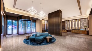 En moderne lobby med en bl å sofa, et rundt sofabord og en lysekrone.