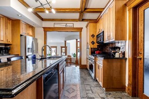 A kitchen with wooden cabinets, a granite countertop, a stainless steel refrigerator, and a built-in oven. - Grand Victorian Farmhouse Escape with Pool, Hot Tub & Fire Pit Nights in Ontario, Canada (Leamington)