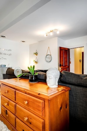 A living room with a wooden dresser, a grey sofa, a white bust sculpture, and wall-mounted decor. - Grand Victorian Farmhouse Escape with Pool, Hot Tub & Fire Pit Nights in Ontario, Canada (Leamington)