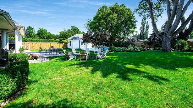 Ein Garten mit Pool, Gartenmöbeln und einem großen Baum.