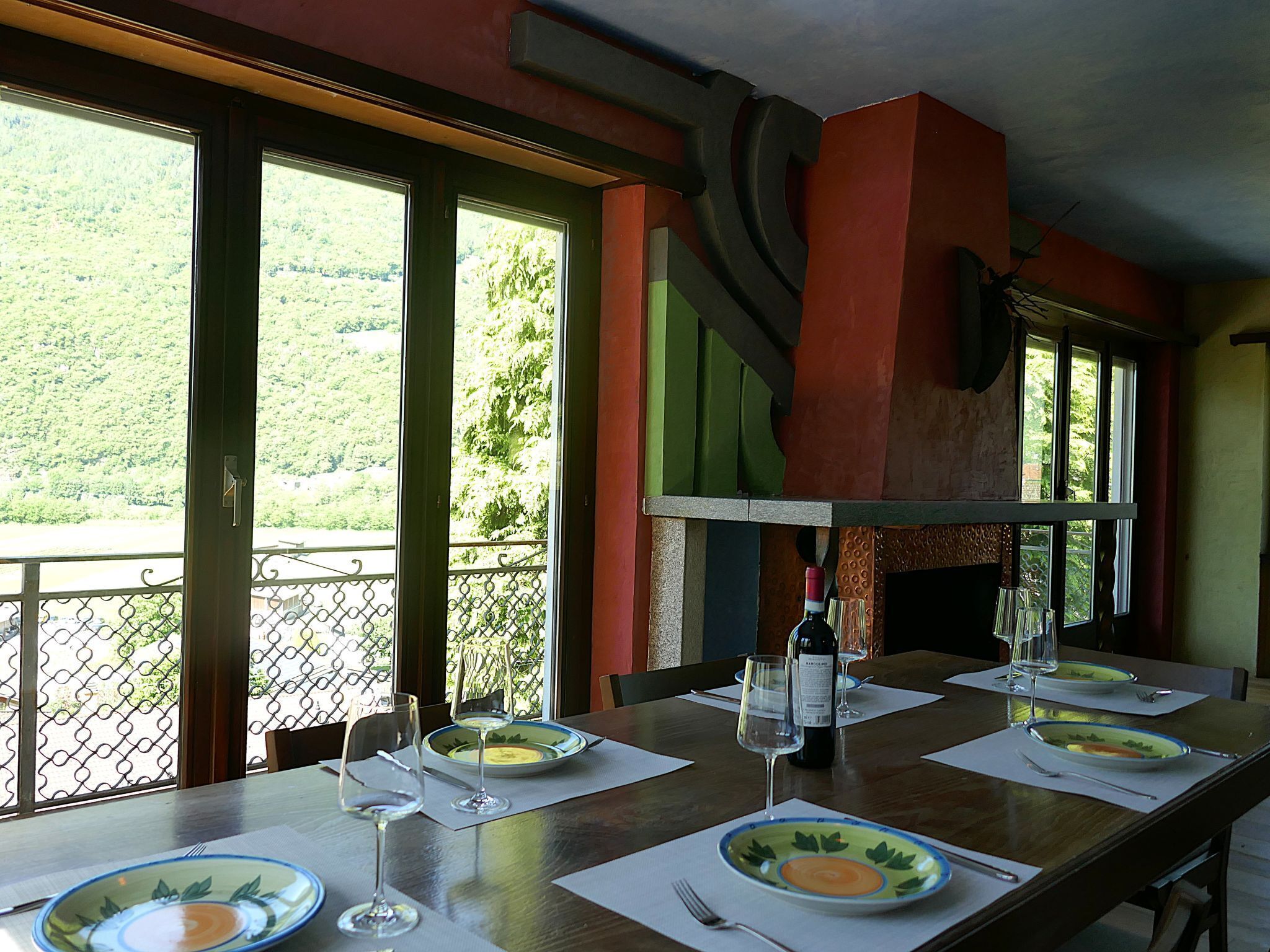 A dining table set with plates, glasses, and a bottle, overlooking a scenic view.