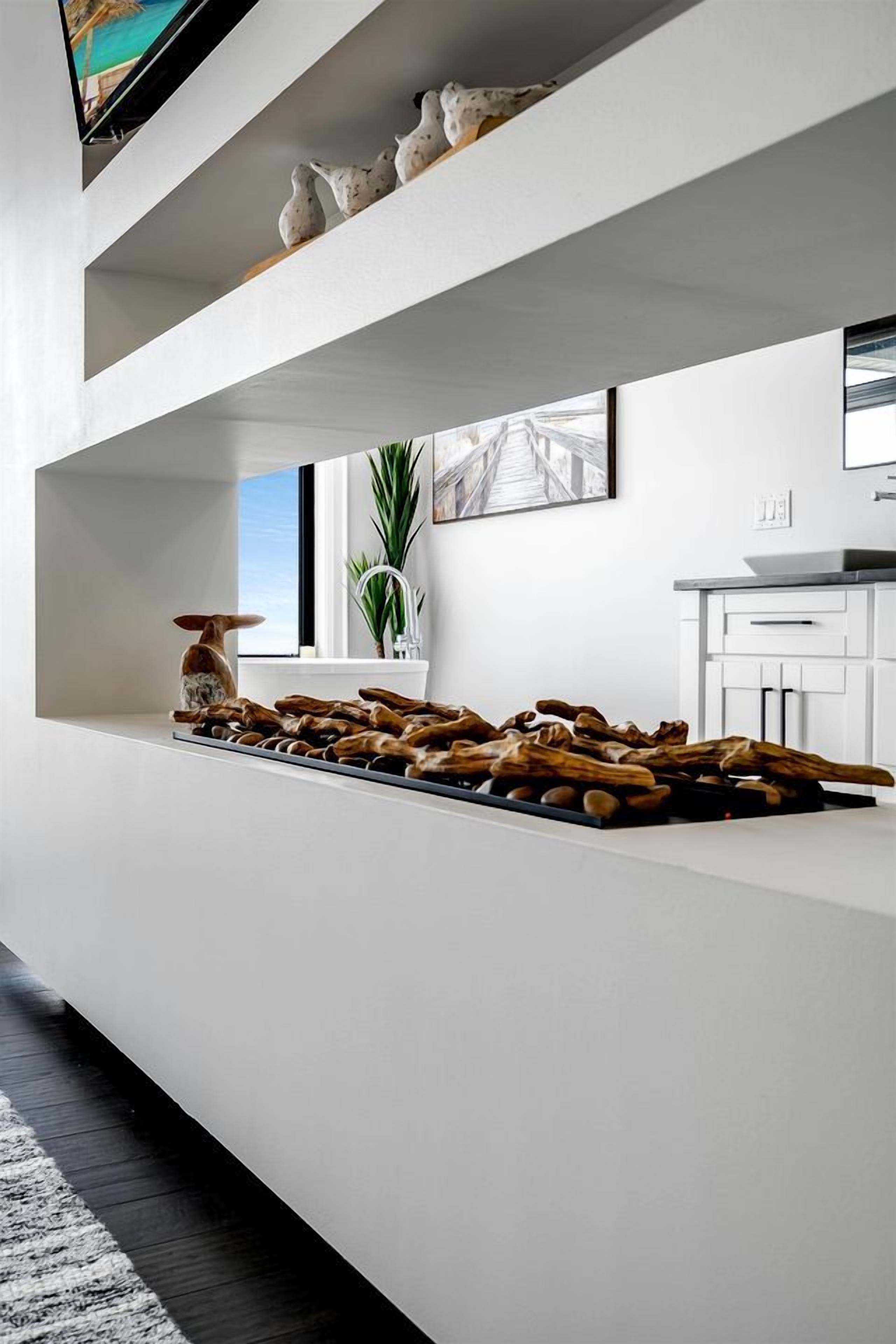 A modern kitchen with white cabinetry, a wooden countertop, and a large window.