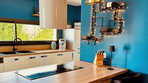 Una cocina moderna con una isla central, taburetes de bar, una cafetera y luces decorativas en la pared.
