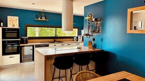 Cocina moderna con una isla grande, taburetes de bar y vista a zonas verdes.