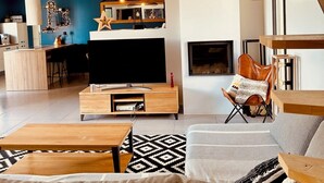 Una sala moderna con sofá, mesa de centro, televisor y chimenea.