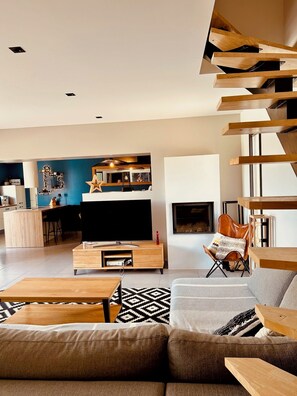 Ein modernes Wohnzimmer mit Sofa, Couchtisch, Fernseher und Kamin.
