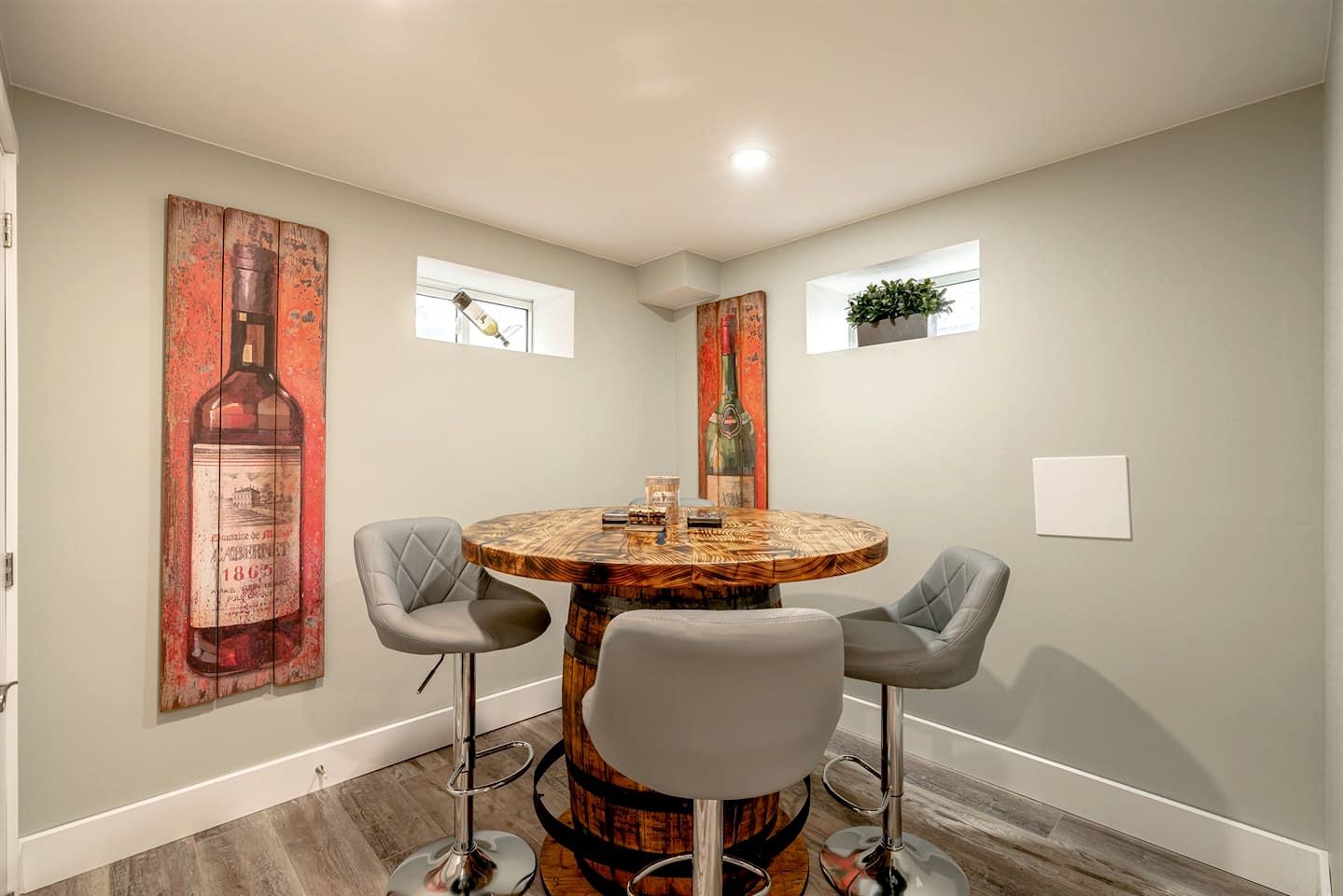 Un coin repas avec une table ronde, deux chaises et un grand tableau accroché au mur.