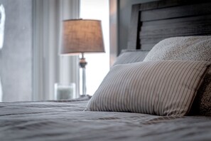 A bed with striped pillows and a wooden headboard in a hotel room.