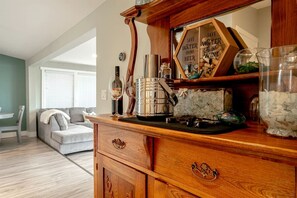 Un coin bar en bois équipé d’une machine à café, de verres à vin et d’un panneau encourageant à économiser l’eau.