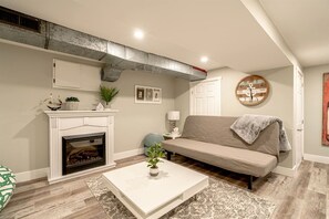 A living room with a fireplace, a sofa, a coffee table, and a clock on the wall.