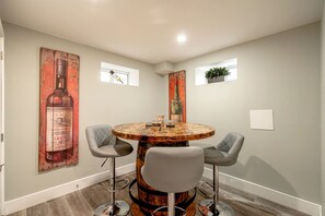 A dining area with a round table, two chairs, and a large painting on the wall.