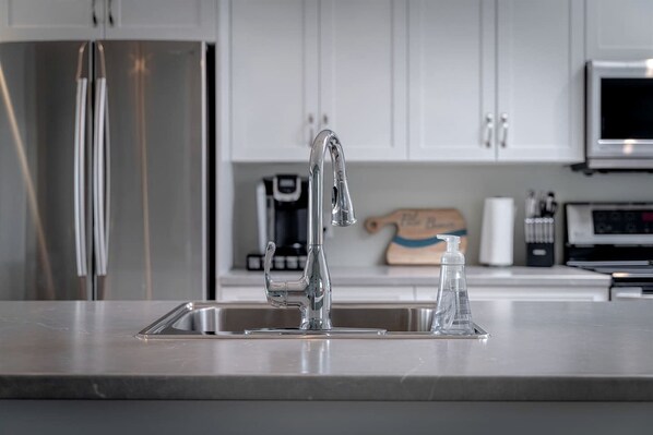 A modern kitchen with stainless steel appliances, a double sink, and white cabinetry.