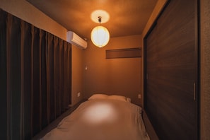 Une chambre à coucher comprenant un lit, un appareil de climatisation, un luminaire fixé au mur et une porte coulissante.