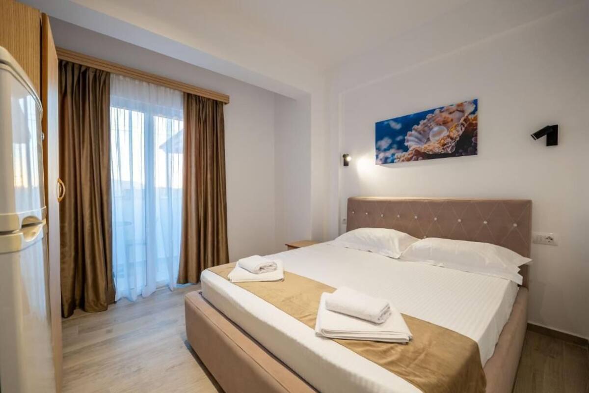 Una habitación de hotel con cama, cortinas, un cuadro y un número en la pared.