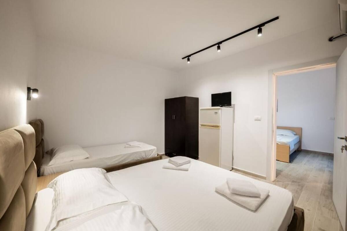 Habitación de hotel con dos camas, un armario, un televisor y un escritorio.