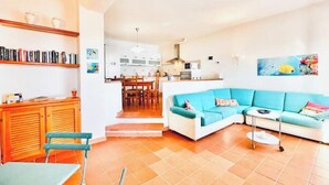 Un soggiorno con un divano blu, un mobiletto in legno e un'area pranzo con sedie.