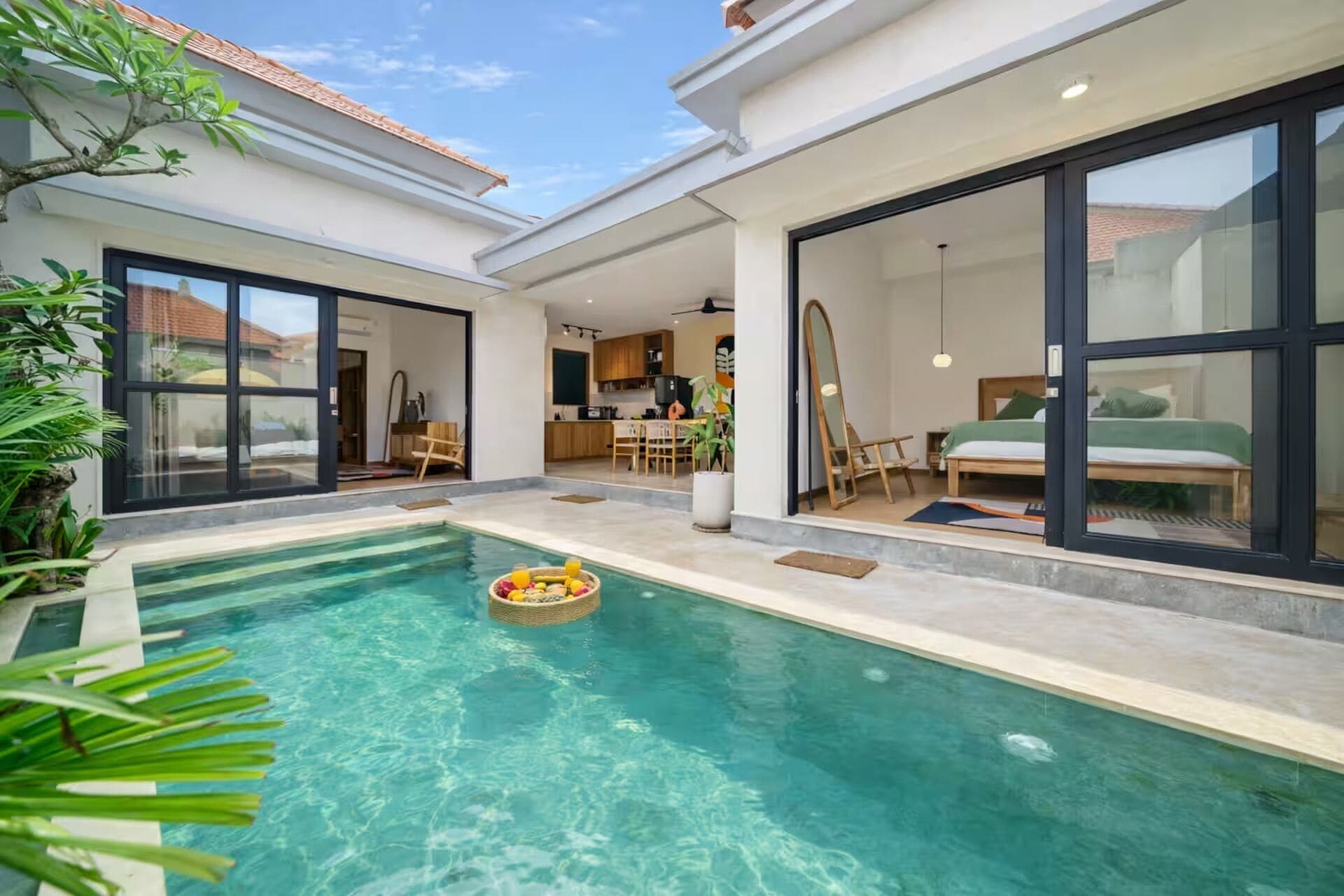 A modern house with a swimming pool, a dining area, and a bedroom with large windows.