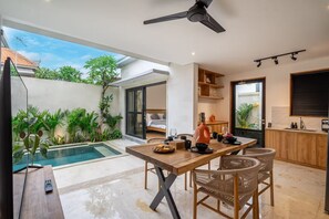 A modern kitchen with a dining area, a pool, and a bedroom. - Lekatika Villa (Kerobokan)