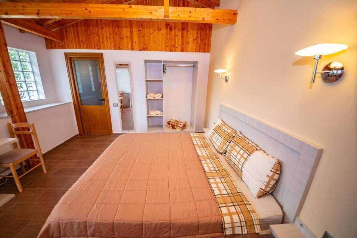 A bedroom with a bed, a chair, a wardrobe, and a window.