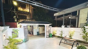 Un patio con un área de descanso cubierta, plantas en macetas y una escalera que conduce a un nivel superior.