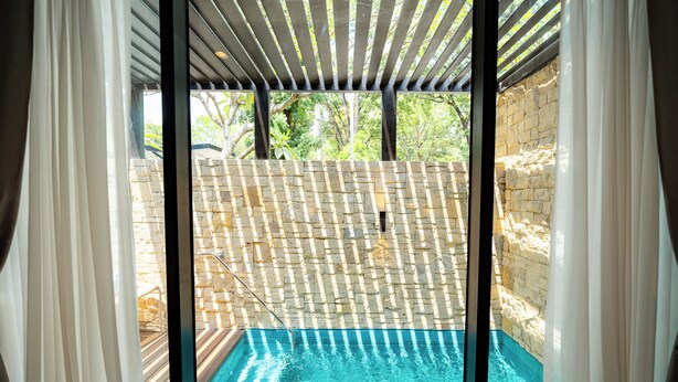 A pool with a stone wall and a wooden deck. - The Henry Glass House Clark (Mabalacat City)