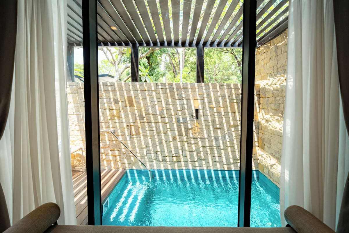 Una piscina con un muro de piedra y una terraza de madera.