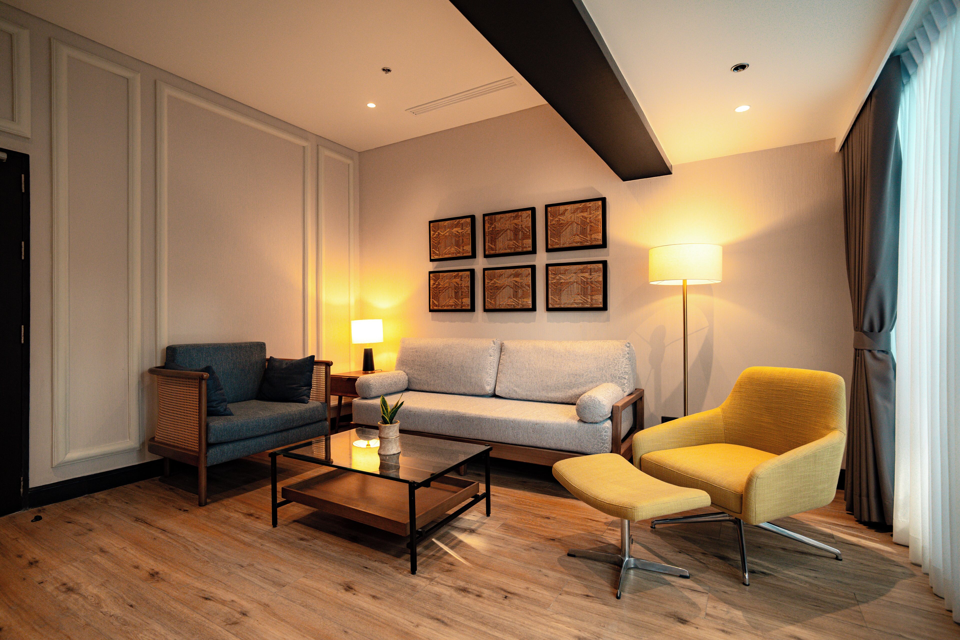 A modern living room with a sofa, armchair, coffee table, and a lamp.