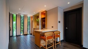 A modern interior with a wooden bar area, two bar stools, and a dark door. - The Henry Glass House Clark (Mabalacat City)