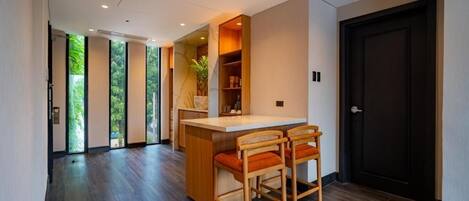 A modern interior with a wooden bar area, two bar stools, and a dark door.
