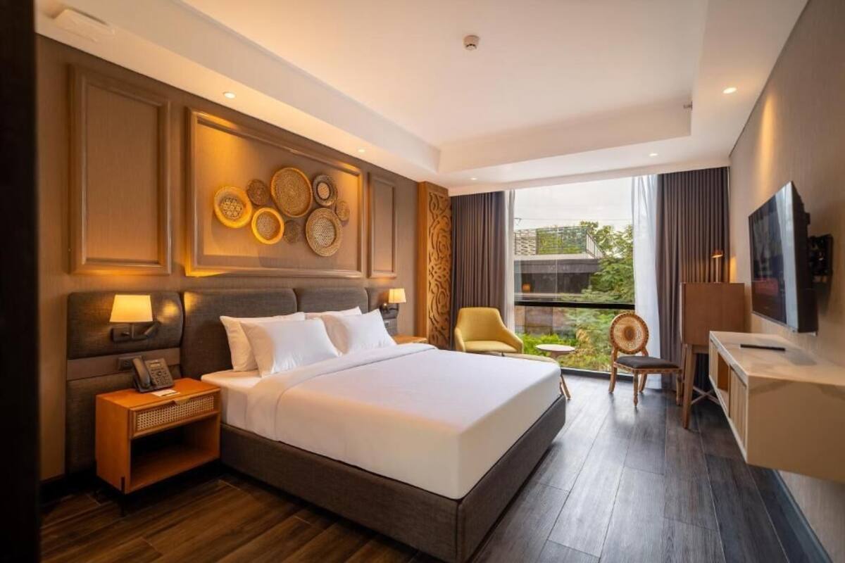 Una habitación de hotel moderna con una cama grande, un escritorio, una silla y un televisor.