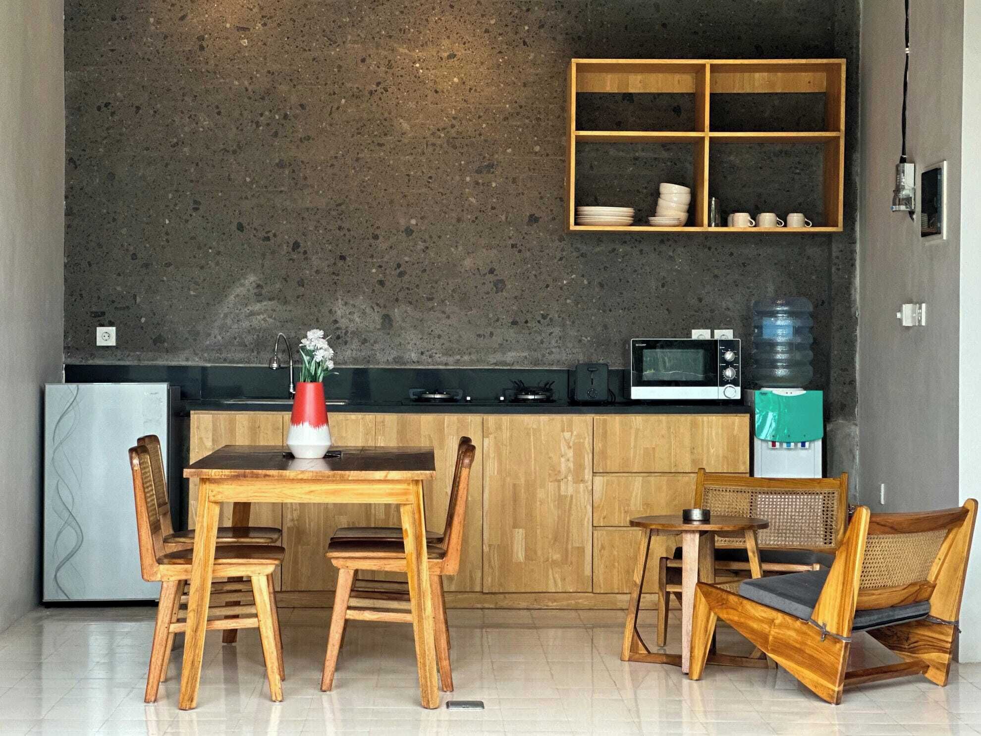 A modern kitchen with a wooden dining table, chairs, a microwave, and a water dispenser.