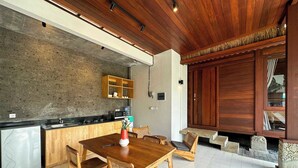 Una cocina moderna con una mesa y sillas de madera, horno empotrado y pared de piedra.