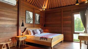 Una habitación con paneles de madera, una cama, una mesita de noche, una mesa y un ventanal con cortinas.