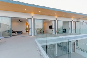 Ein modernes Interieur mit Glastrennwand, einer Sitzecke mit Sofas und einem an der Wand befestigten Flachbildfernseher.