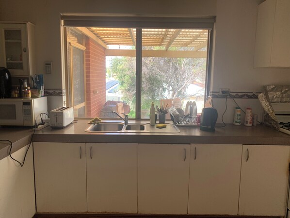 A kitchen with a window, a microwave, a toaster, a sink, and cabinets.