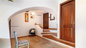 Un couloir avec une chaise, une porte en bois et un escalier.