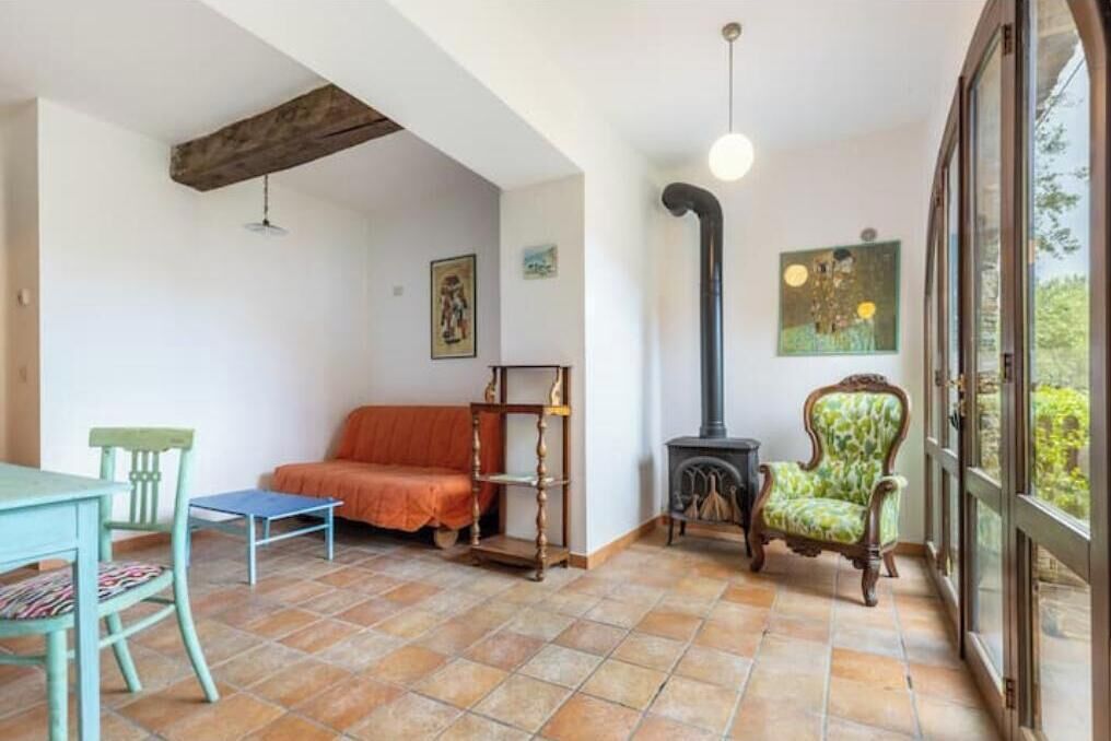 A room with a fireplace, a sofa, a chair, a table, and a window.