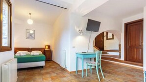 Une chambre à coucher comprenant un lit, un bureau avec une chaise, une télévision et un escalier menant à une autre pièce.