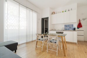 Een moderne keuken met witte kasten, een glazen eettafel en een houten vloer.