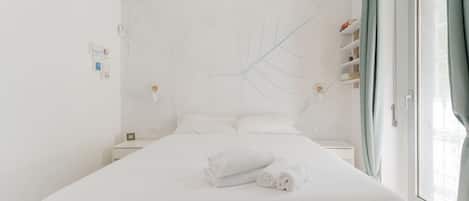 A hotel room with a large bed, a nightstand, a map on the wall, and a window with curtains.