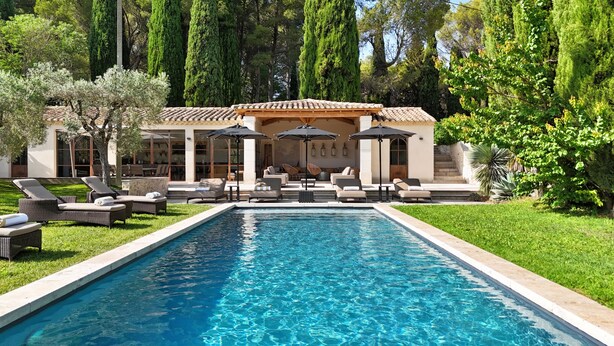 A swimming pool with lounge chairs and umbrellas, surrounded by greenery and tall trees. - Domaine de la Rose Comtesse - Luxe (Ventabren)