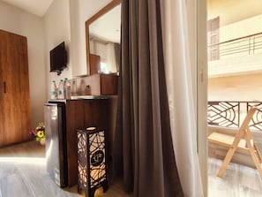 A hotel room with a wooden wardrobe, a minibar, a small table with a lamp, a mirror, and a view of the outside balcony. - tourist hotel cairo downtown (Cairo)