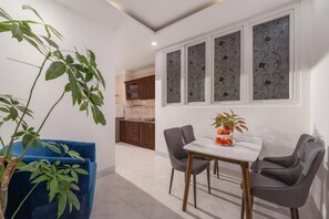 A dining area with a table, chairs, and a potted plant. - Miami Beach Hotel & Apartment (Ngu Hanh Son)